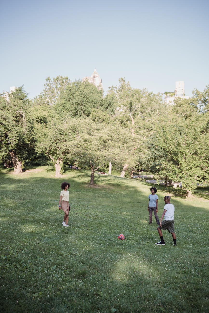 three teenagers playing football in the park