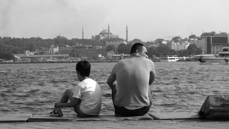 son and father sitting on pier in istanbul