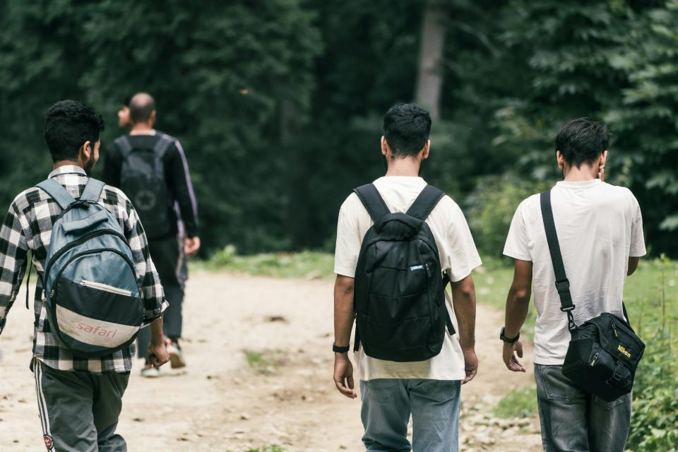 a group of men with backpacks walking in a forest