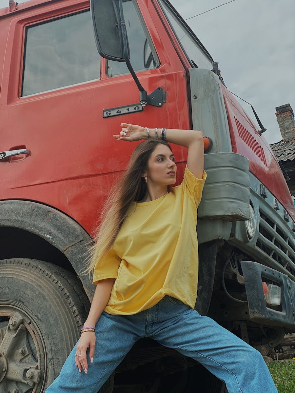 woman in yellow t shirt and blue denim jeans posing beside red truck