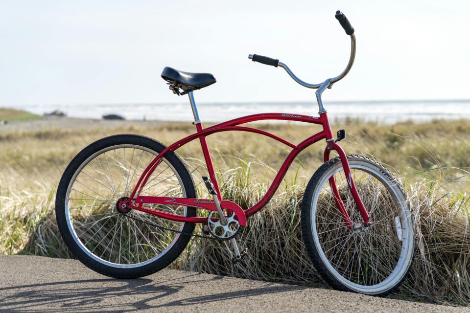 photo of red bike parked on road beside grass field