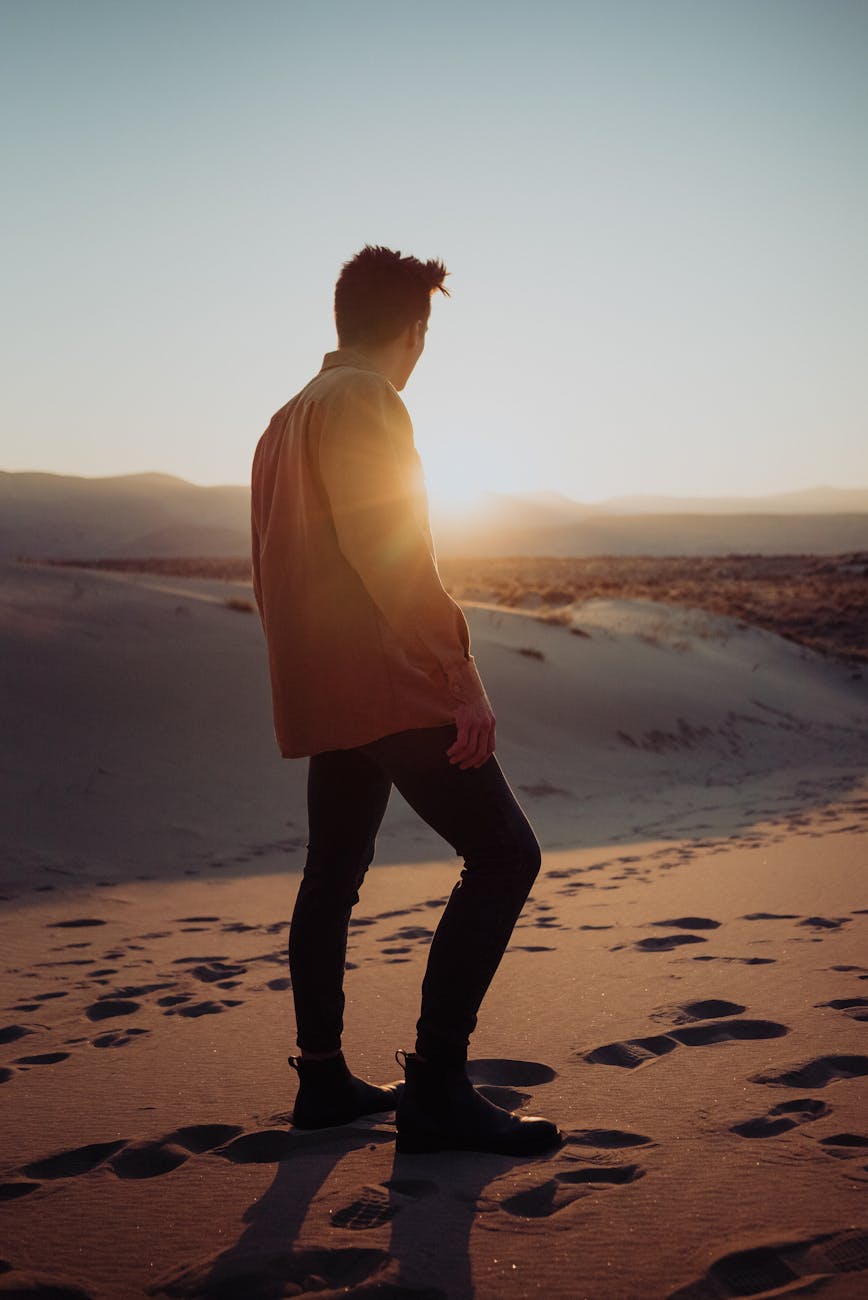 anonymous man walking on sandy dunes in desert