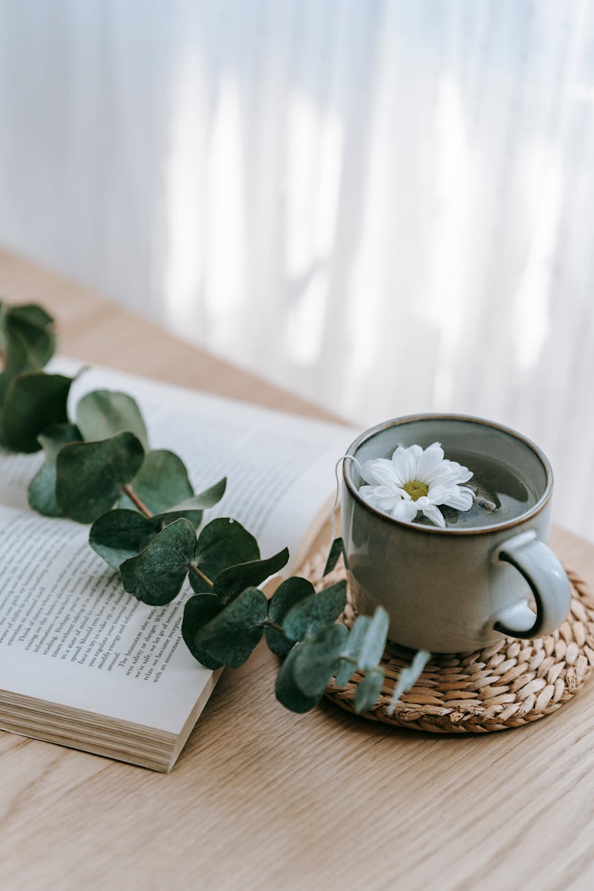 cup of tea on table near book and plant stem