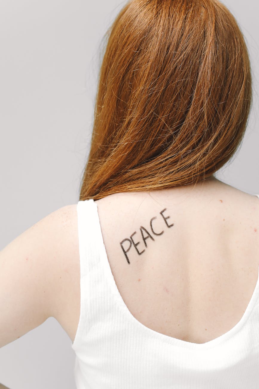 woman in white tank top with word peace written on her back
