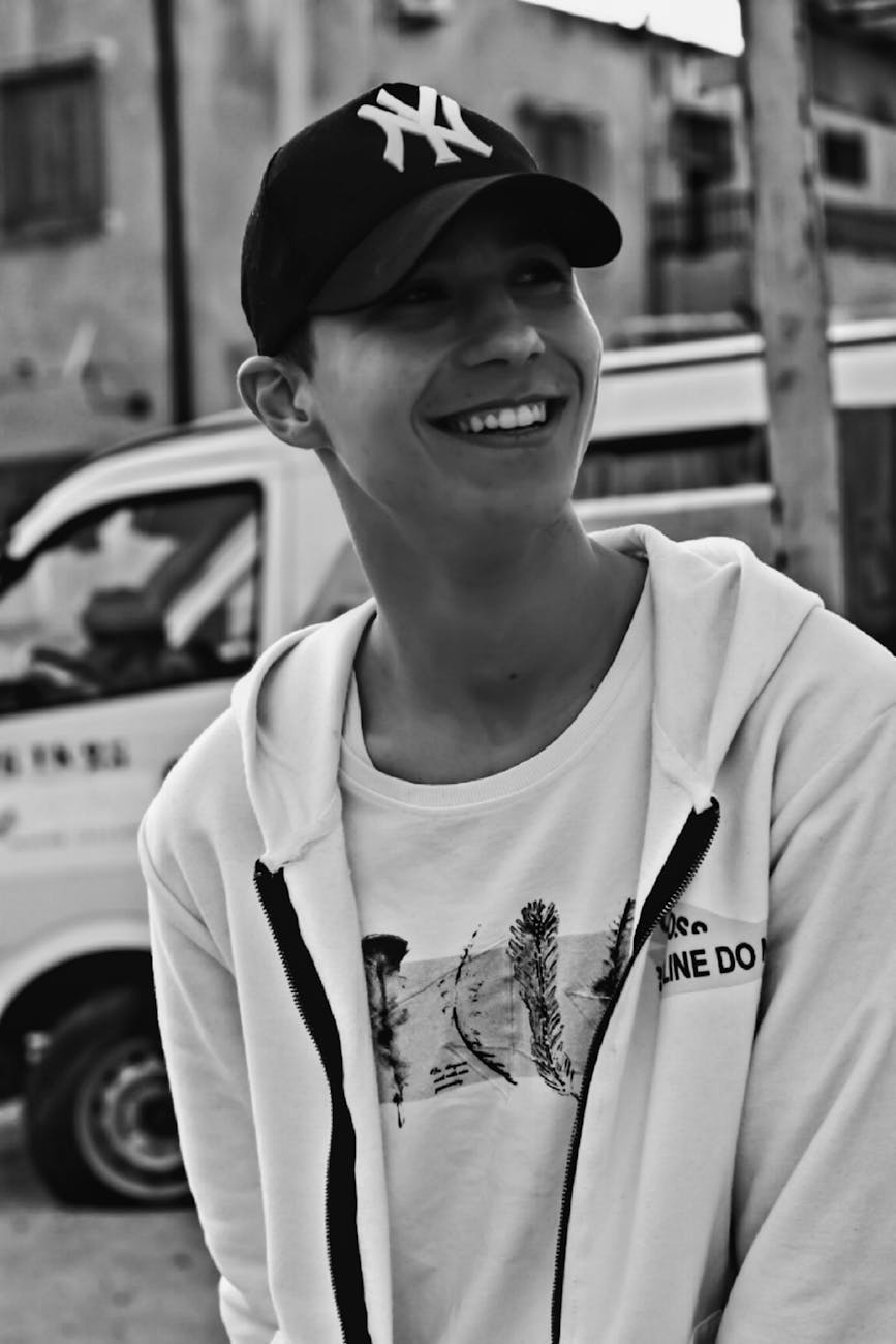 grayscale photo of a man with cap smiling