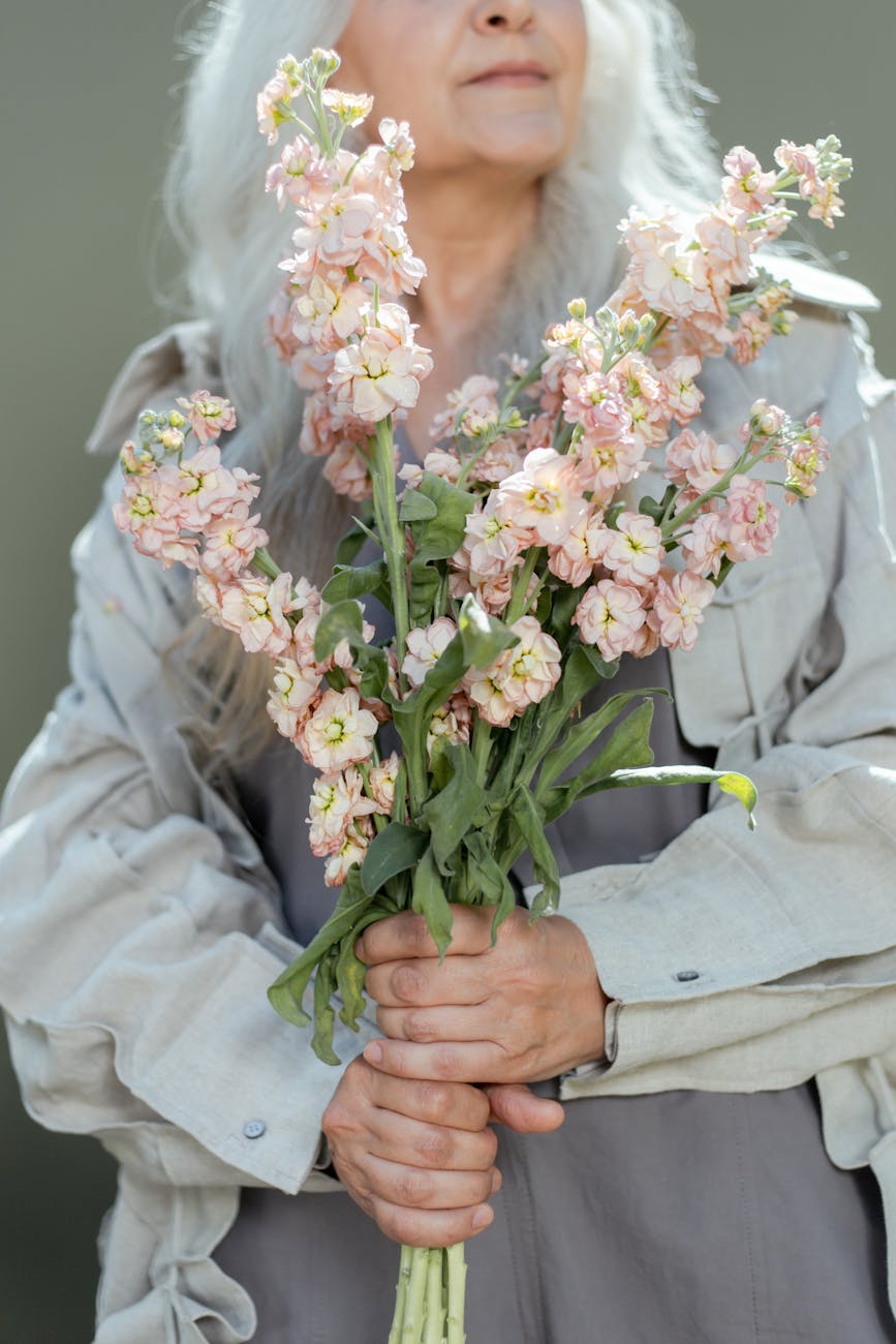 photo of an elderly woman holding hoary stock flowers