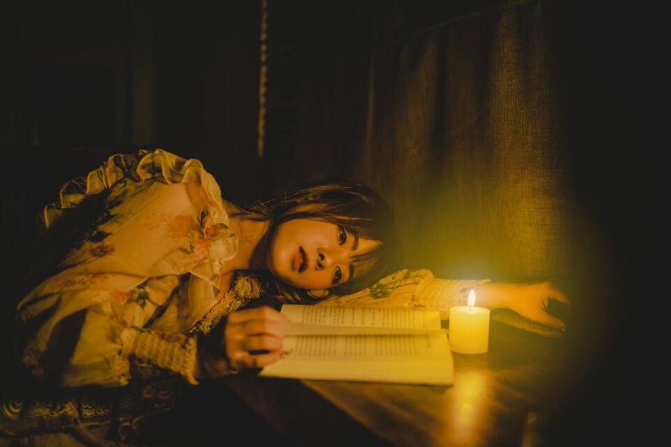 woman lying down on table with wax candle and reading