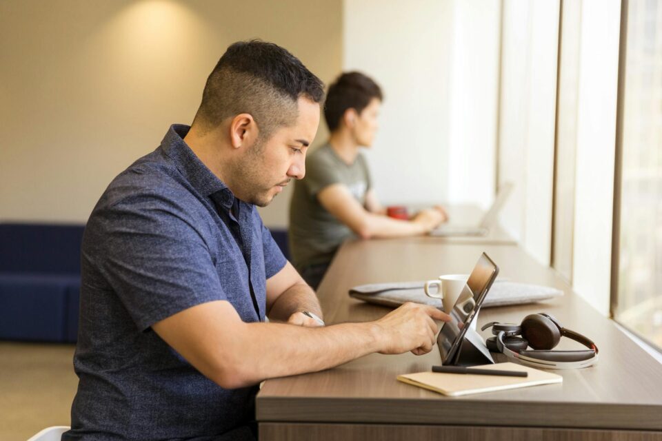 man sitting on white chair pointing on tablet screen inside room