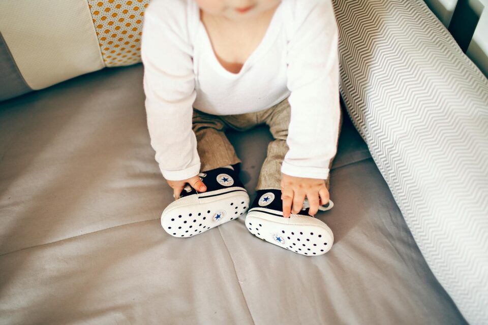 little baby in cool shoes on bed