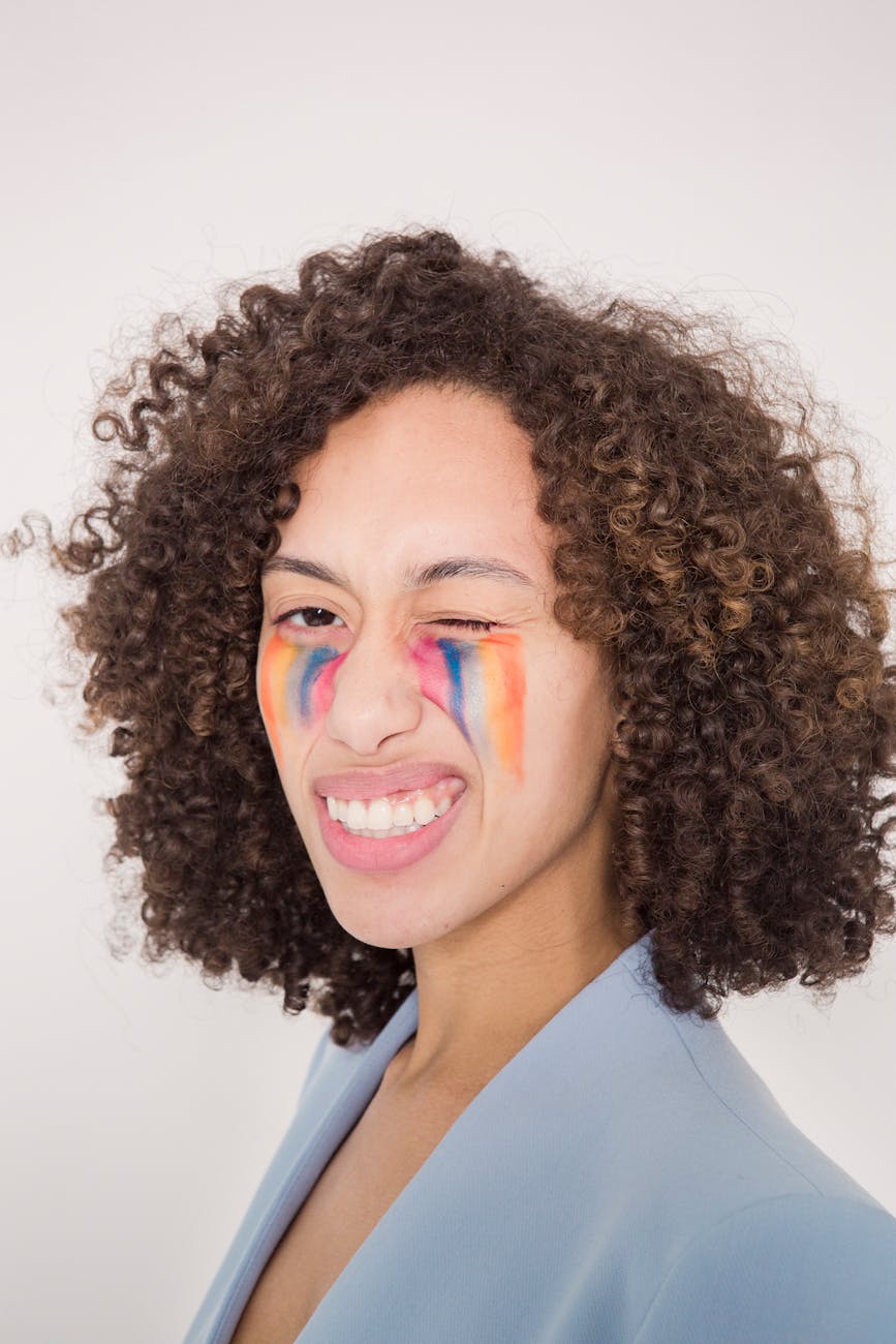confident ethnic woman with colorful paint smears on face looking at camera