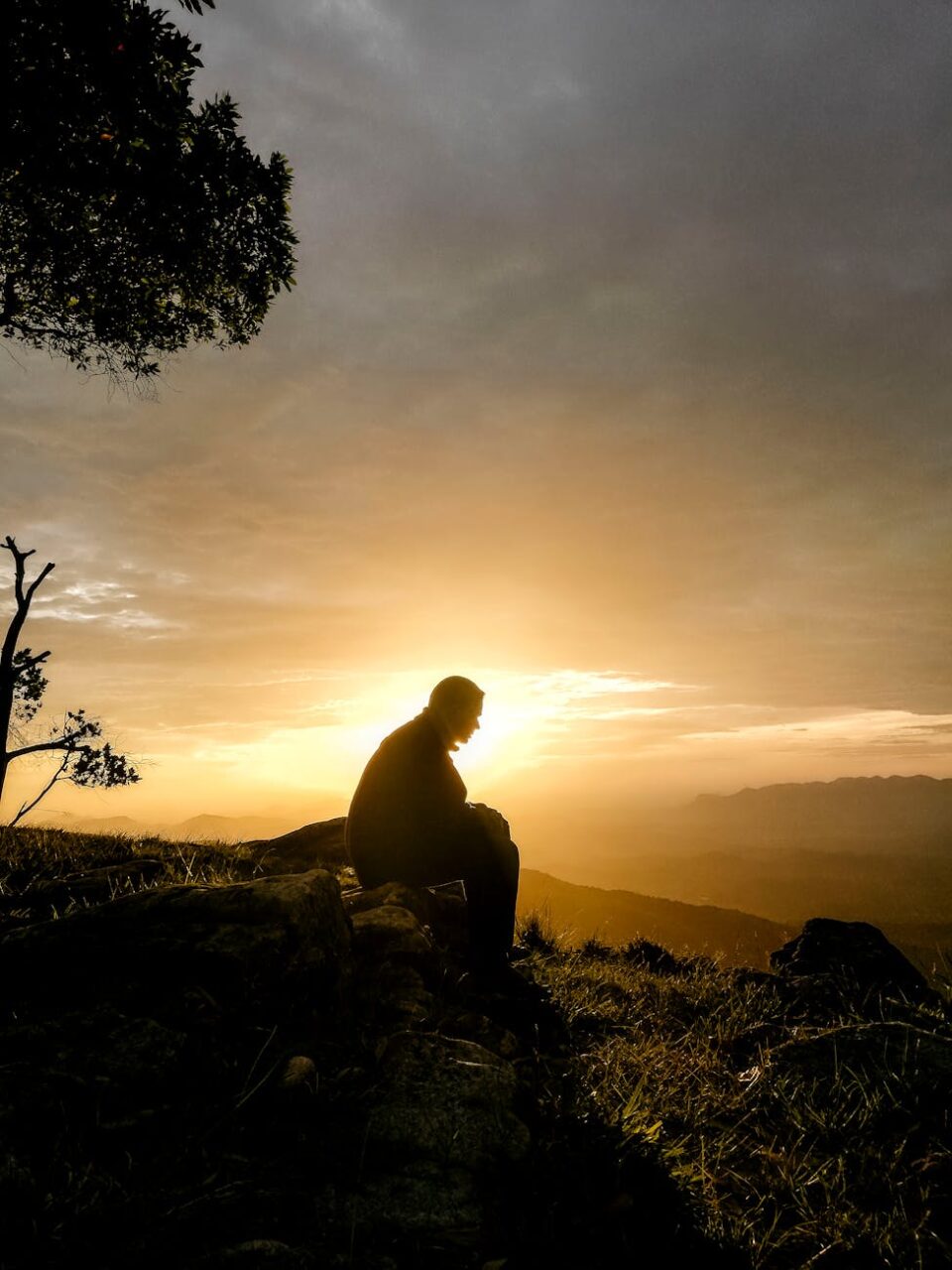 silhouette of man sitting on the stone during sunrise