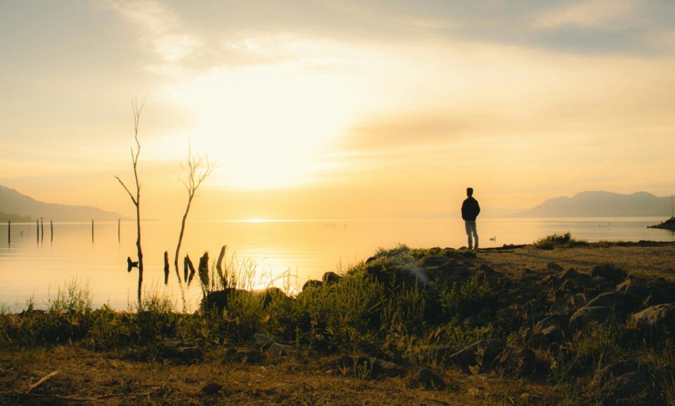 man standing on the coast with a view of the sea at sunset