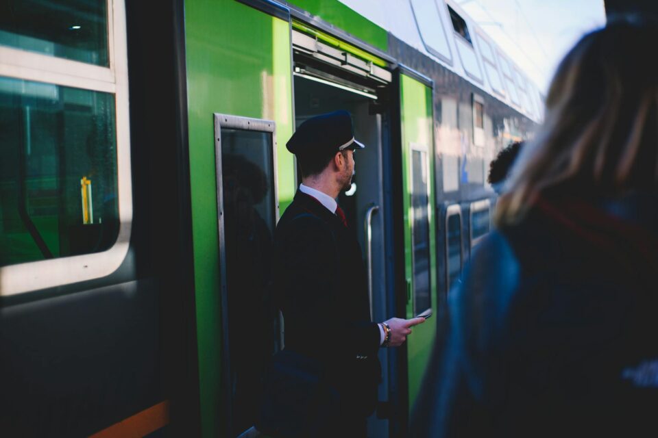 man in black suit standing beside train