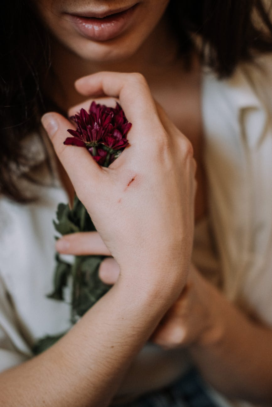 crop woman with scratch on hand touching daisy flower