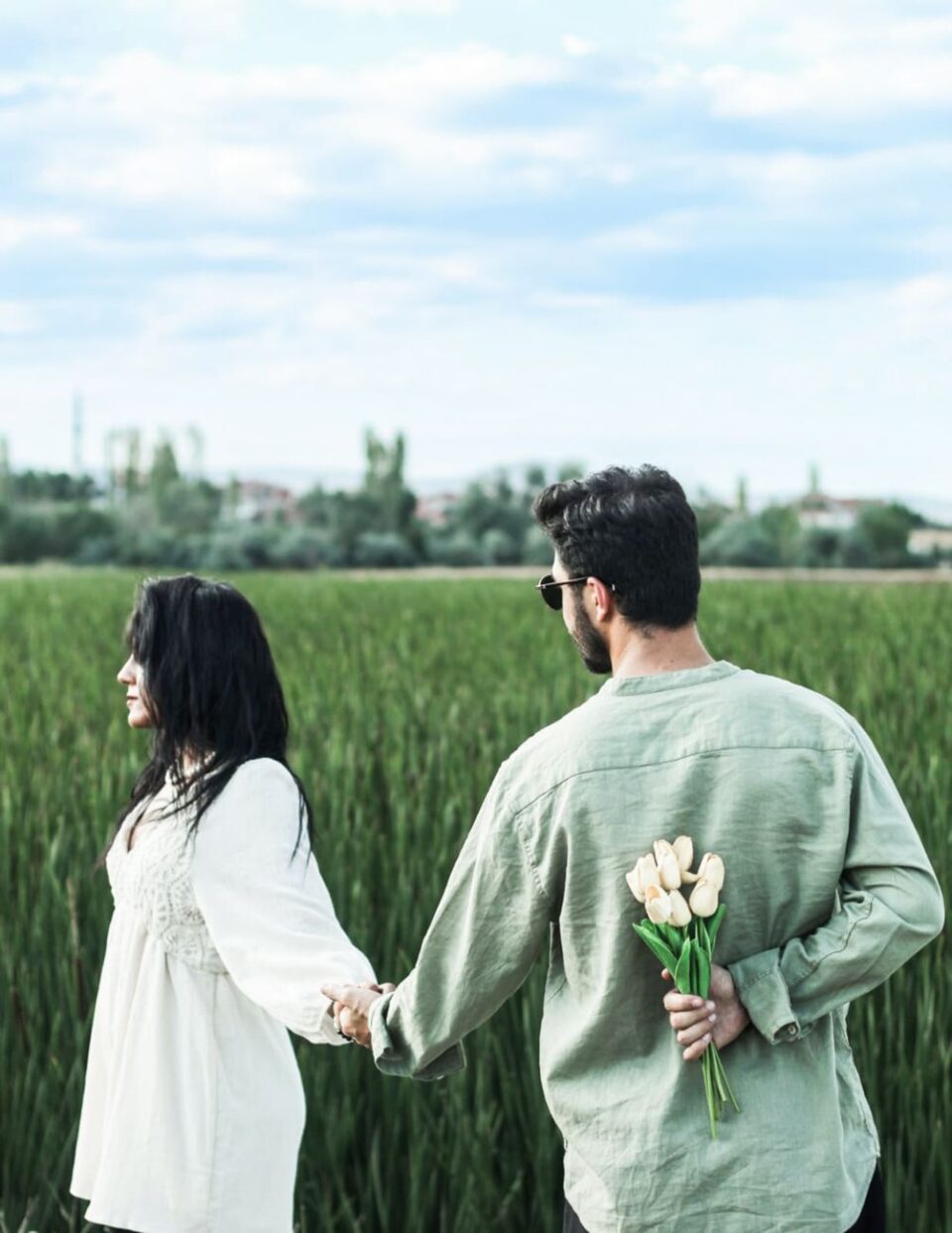 a young couple standing on a field and holding hands
