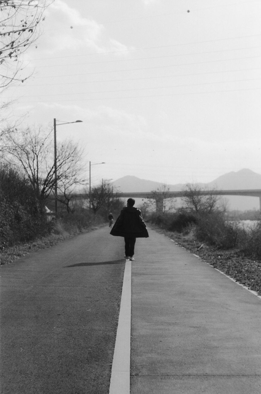 monochrome figure on empty path with bridge