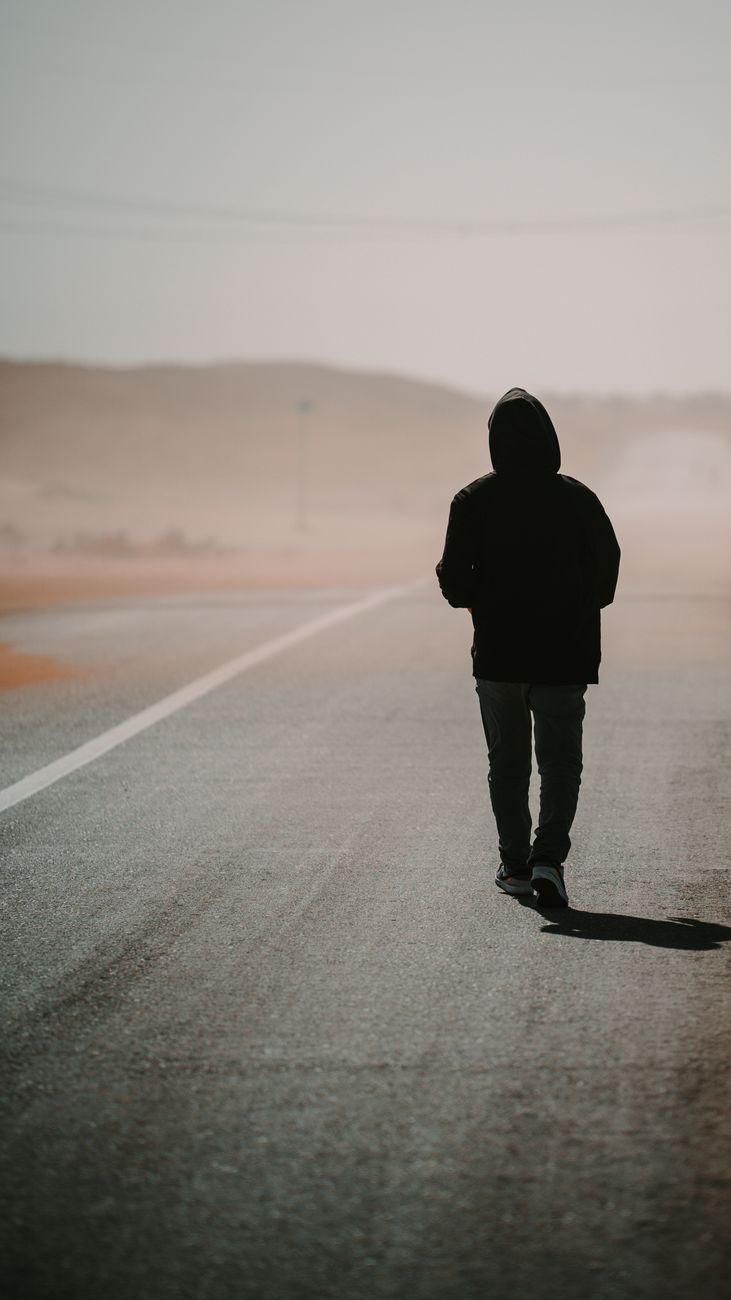 solitary figure walking on desert highway