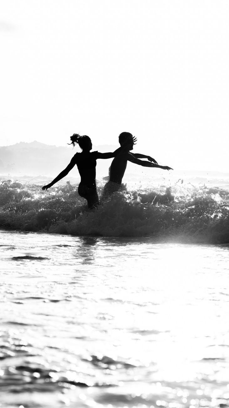 a two people running on the sea waves