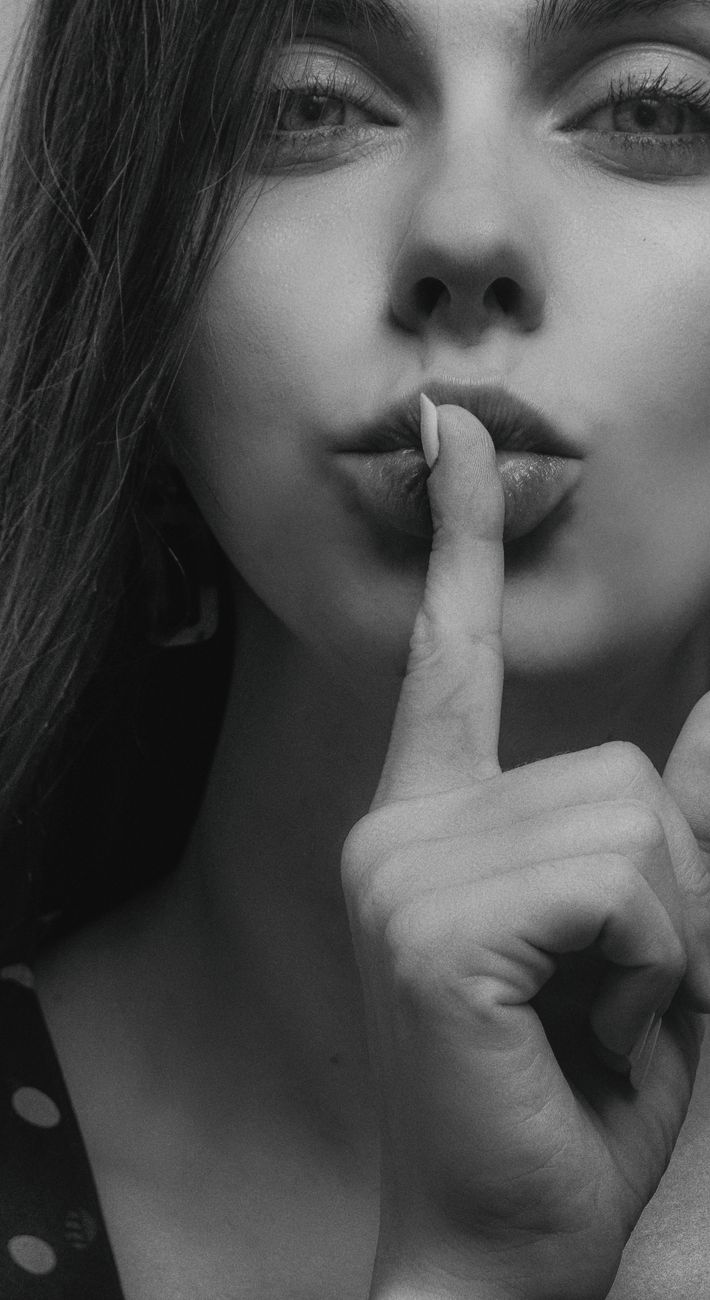 grayscale photo of a woman doing a quiet hand gesture